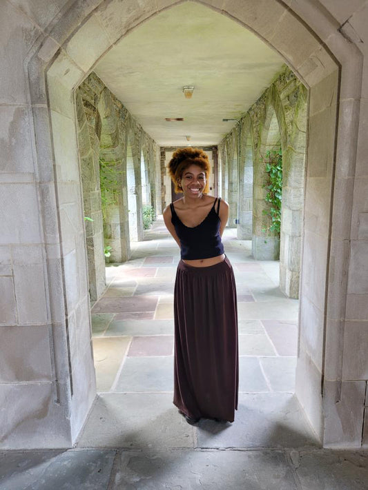 A girl with a thoughtful expression stands at a pathway, surrounded by pillars designed to push you in a specific direction. Her blog captures the essence of her girlhood journey.